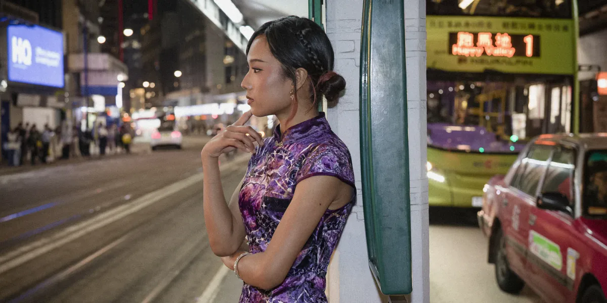 Lia stands in profile beside tram tracks, with a tram and a red taxi behind her